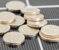 Makro-Aufnahme eines Photovoltaik-Moduls mit Münzen darauf als Symbol für die Solar-Förderung
