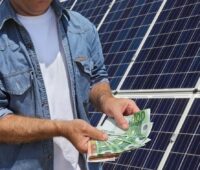 Im Bild ein Mann mit Geldscheinen vor Solaranlage als Symbol für die Finanzierung von Sunvigo durch die Triodos Bank.