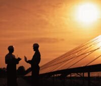 Planer mit Schutzhelm im Solarpark bei Sonenuntergang