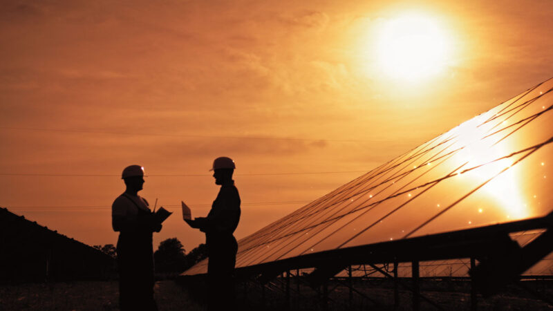 Planer mit Schutzhelm im Solarpark bei Sonenuntergang