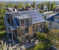 Haus im dörflichen Umfeld mit PV auf den Schrägdächern.