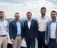 Offizielle auf einem Balkon bei der Vertragsunterzeichnung des Hybrid-PPA für das Photovoltaik-Batteriespeicher-Co-Location-Projekt mit garantiertem Mindesterlös.