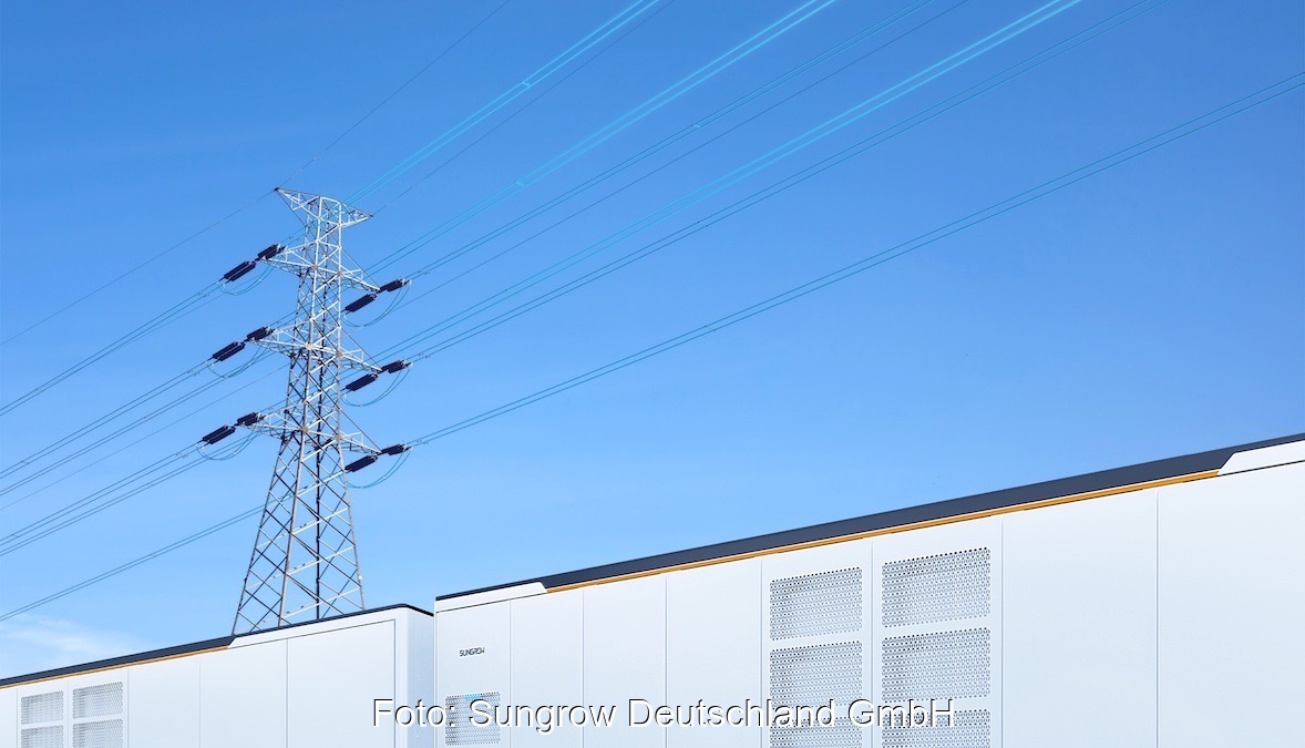 Ein im Vordergrund angeschnittener Batteriespeicher PowerTitan 2.0 in lichtgrau vor blauem Himmel. Im Hintergrund eine Strommast.