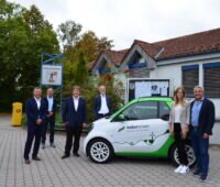 Menschen in Hemhofen mit Auto mit Naturstrom-Aufschrift - Naturstrom soll die Kunden künftig mit Solarstrom aus der Region beliefern.