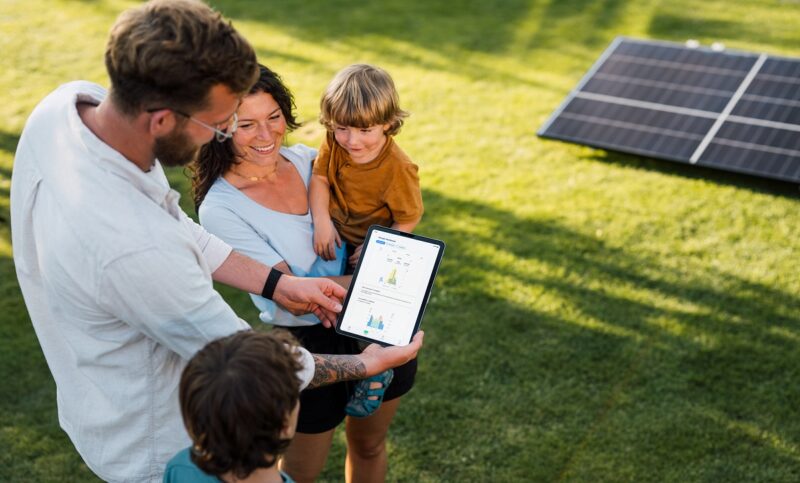 Im Bild eine Familie mit einem Tablett, auf der die Orbit Energiemanagement-App für Balkonkraftwerke läuft.