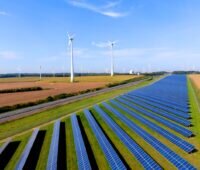 Solarfreifläche und Windenergieanlagen im Flachland bei Sonnenschein.