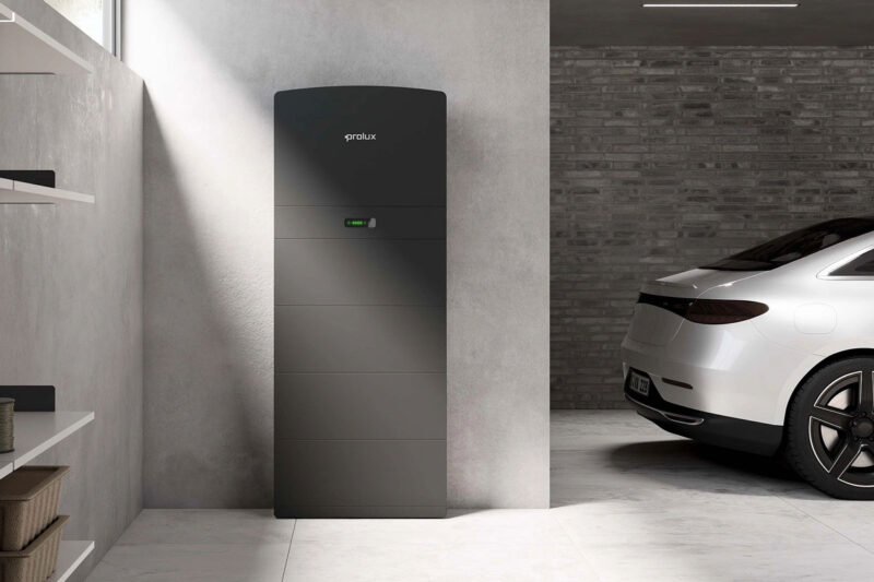 Prolux Storac LFP Batteriespeicher steht in einer sehr aufgräumten Garage mit Elektroauto.