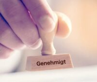 Im Bild eine Hand mit Stempel „genehmigt“ als Symbol für das Förderprogramm Klimaschutzverträge.