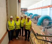 Fünf Personen in Sicherheitswesten und Helmen in Maschinenhalle eines Pumpspeicherkraftwerks.