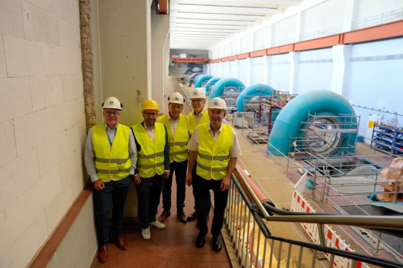 Fünf Personen in Sicherheitswesten und Helmen in Maschinenhalle eines Pumpspeicherkraftwerks.