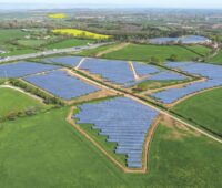 Luftaufnahme zeigt Solarparks umgeben von grünen Feldern entlang einer Autobahn