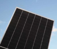Schwarzes Solarmodul vor blauem Himmel.