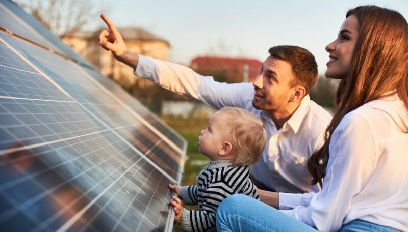 Im Bild Vater, Mutter und Kind mit Photovoltaik-Anlage, für die Qcells nun eine Versicherung mitliefert.