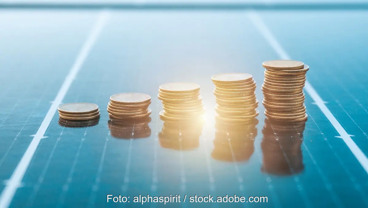 Stapel von Geldmünzen auf Photovoltaik-Modulen.