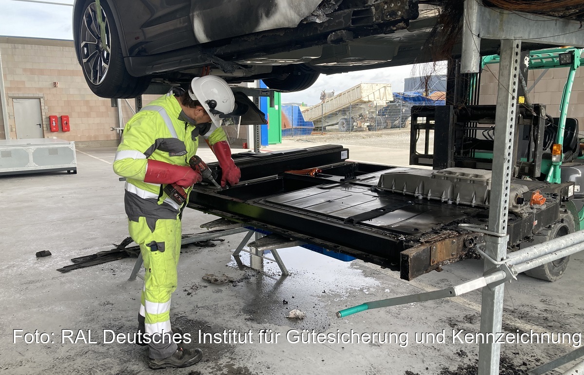 Ein Monteur entfernt die Autobatterie eines Unfallwagens, das RAL Gütezeichen Havarie Elektromobilität und Energiespeicher soll für einen sicheren Umgang mit Batterien im Schadensfall sorgen.