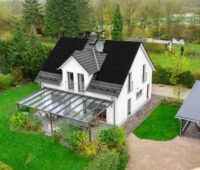 Blick auf ein freistehendes Einfamilienhaus mit Schrägdach, auf dem schwarze Module installiert sind.