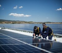 Zu sehen sind Arbeiter auf dem Dach. Es handelt sich um eine der 10 GW installierte Photovoltaik-Leistung von REC.