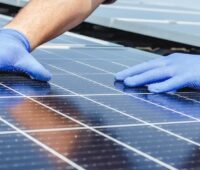 Zwei Hände streichen über ein PV-Modul als Symbol für den geplanten Photovoltaik-Solarpark in Limbach.
