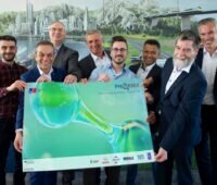 Mehrere Beteiligte des Wasserstoffmotor-Projektes Phoenix halten einen überdimensionierten Förderbescheid in die Kamera.