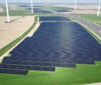 Luftaufnahme des RWE-Solarprojekts entlang der A44n: Dichte Reihen von Solarmodulen liegen neben der Autobahn, umgeben von Feldern und mehreren Windenergieanlagen.
