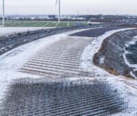 Schneebedeckte Agri-PV-Anlage am Rande einer Autobahn aus der Vogelperspektive.