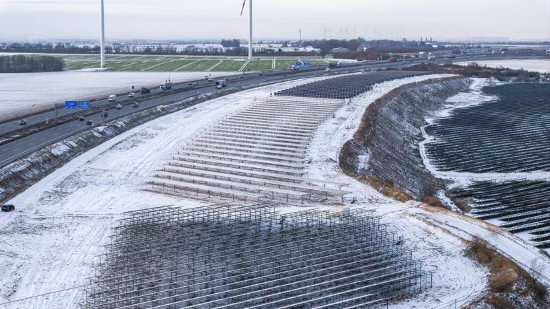 Schneebedeckte Agri-PV-Anlage am Rande einer Autobahn aus der Vogelperspektive.