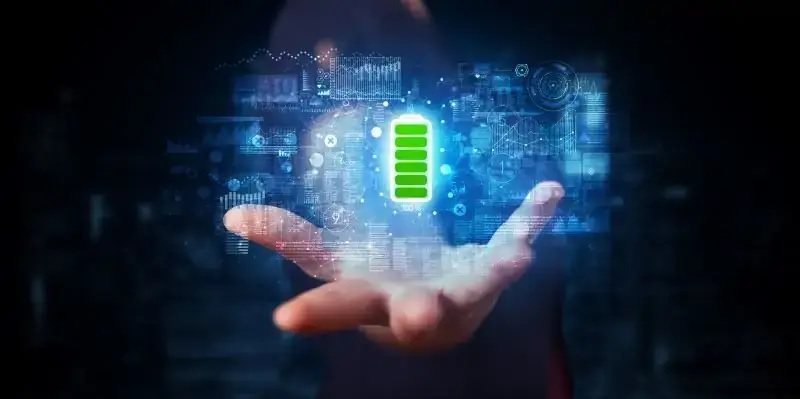In einer bläulich gefärbten virtuellen Umgebung schwebt ein grün leuchtendes Batteriesymbol über einer geöffneten menschlichen Hand.