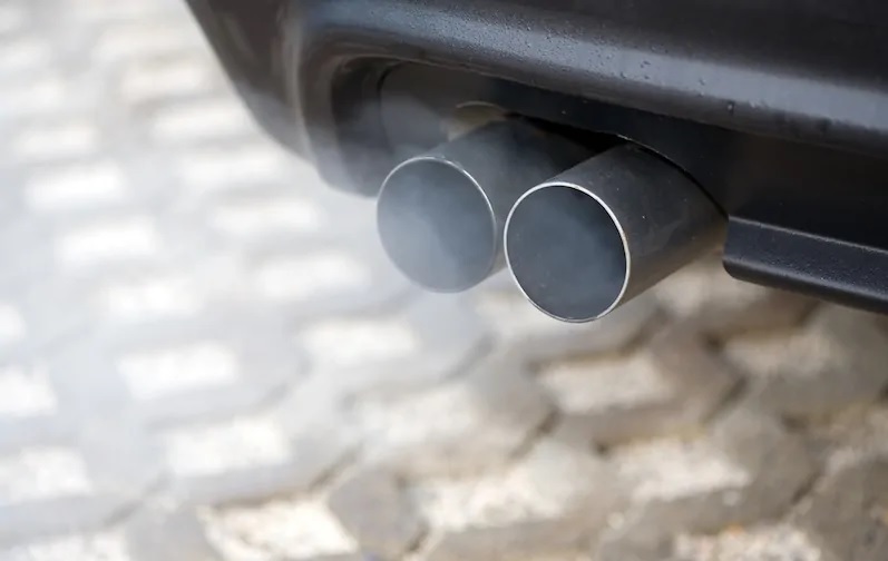 Zu sehen ist ein Auto-Auspuff, das Kohlendioxid das er ausstößt, soll durch Abscheidung von Kohlendioxid aus der Luft wieder eingefangen werden.