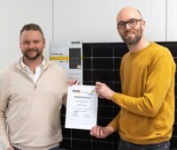 Andreas Bauer und Steffen Binzel halten zusammen den neu geschlossenen Rahmenvertrag in Papierform hoch. Im Hintergrund ist ein Bauer-Modul zu sehen.