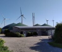 Biogas- und Windkraftanlagen vor einem Flachgebäude