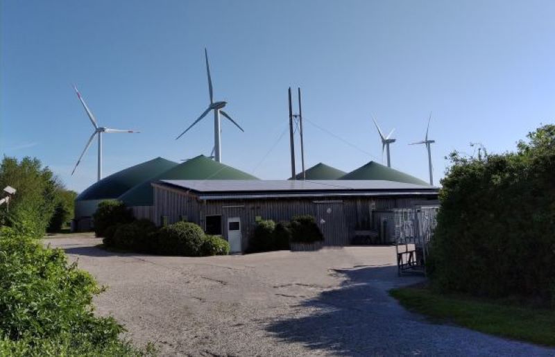 Biogas- und Windkraftanlagen vor einem Flachgebäude