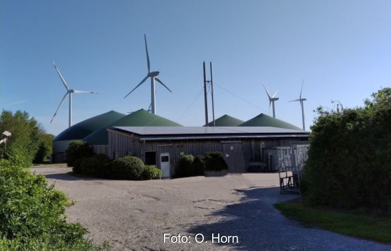 Biogas- und Windkraftanlagen vor einem Flachgebäude