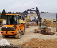 Zu sehen ist ein Bagger auf der Baustelle für die Heizzentrale, in die die größte Solarthermie-Dachanlage Deutschlands die Wärme einspeisen soll.