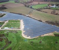 Luftbild einer Freiflächen-Solaranlage auf flachem Terrain.