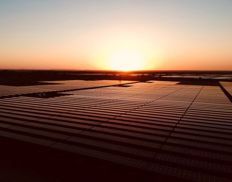 Sonnenuntergang über einem in rotes Licht getauchten Solarpark