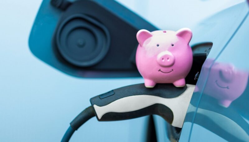 Im Bild ein Sparschwein auf einem Ladekabel eines E-Autos als Symbol für den Handel mit der THG-Quote für Stadtwerke und EVU.