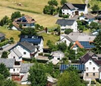 Zu sehen ist ein Dorf mit Photovoltaik-Anlagen, die im Sonnenschein stehen und nicht von Hochwasser betroffen sind.