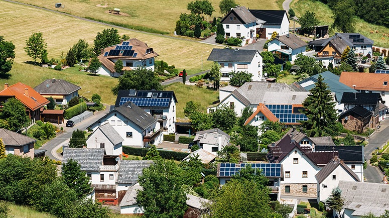 Zu sehen ist ein Dorf mit Photovoltaik-Anlagen, die im Sonnenschein stehen und nicht von Hochwasser betroffen sind.