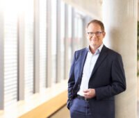 Mann im Anzug vor Fensterfront - SMA-Vorstandsvorsitzender Jürgen Reinert