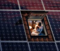 Offenes Dachfenster von oben eingerahmt mit Photovoltaikmodulen mit Blick auf Frau und Kind.