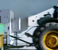 Traktor passiert eine Kombination von weißem SMA-Speicher und -Wechselrichter vor einer weißen Wand.