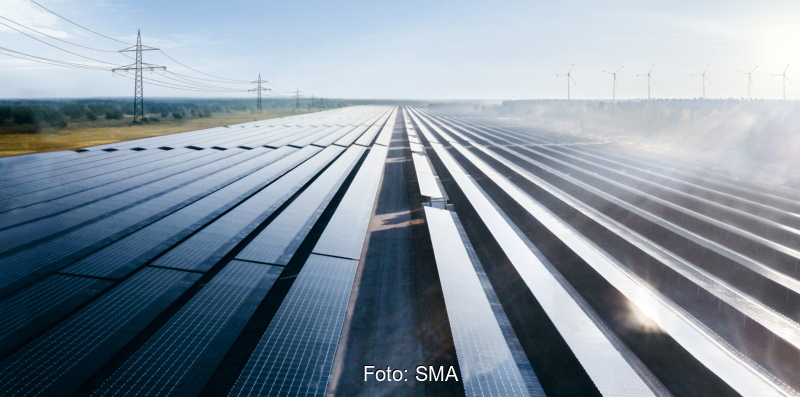 Eine Reihe von Solarstromanlagen zwischen zwei Hochspannungsmasten.