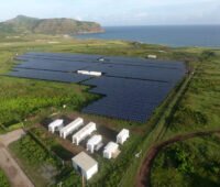 Luftaufnahe Solarpark mit Technik-Containern - Hintergrund: Karibische See