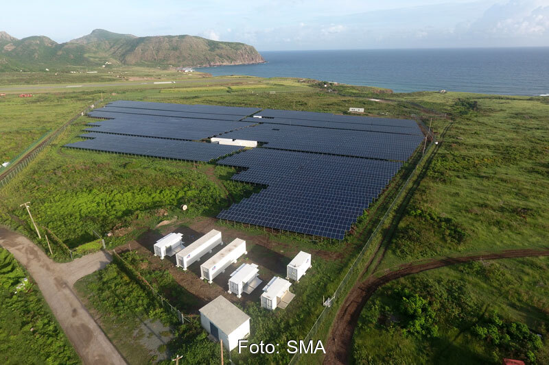 Luftaufnahe Solarpark mit Technik-Containern - Hintergrund: Karibische See