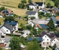 Luftbild zeigt Dorf mit Häusern und PV-Dächern.