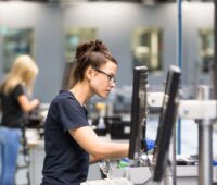 Zwei Frauen arbeiten an der Produktion von Wechselrichtern in einer Fabrikhalle.