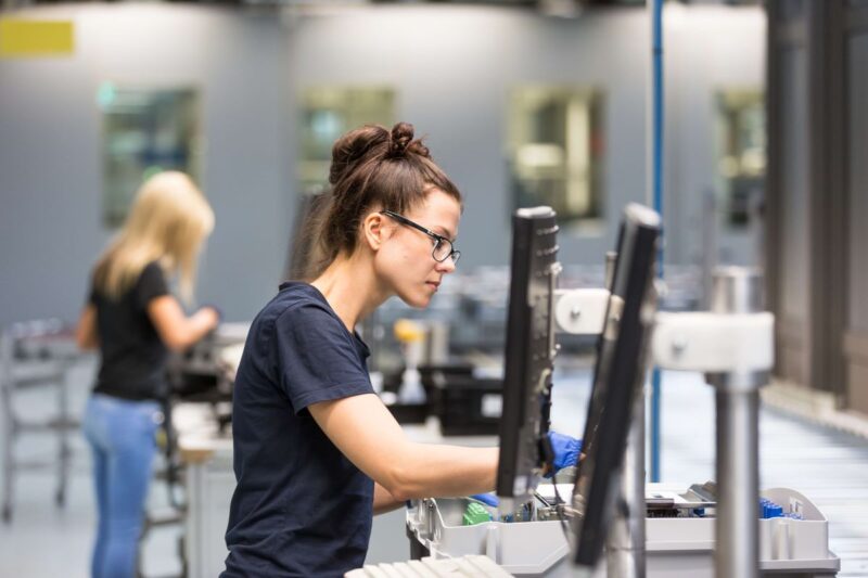 Zwei Frauen arbeiten an der Produktion von Wechselrichtern in einer Fabrikhalle.