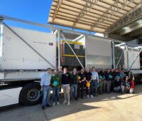 LKW mit großen elektrotechnischen Komponenten und SMA-Mitarbeitern davor.