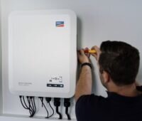 Ein Installateuer montiert SMA-Wechselrichter Sunny Tripower Smart Energy