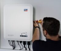 Ein Installateuer montiert SMA-Wechselrichter Sunny Tripower Smart Energy